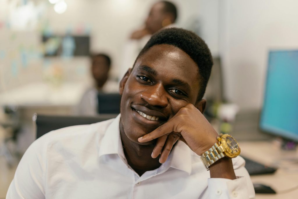 Close-up of a smiling man in a white shirt, relaxed in an office environment.