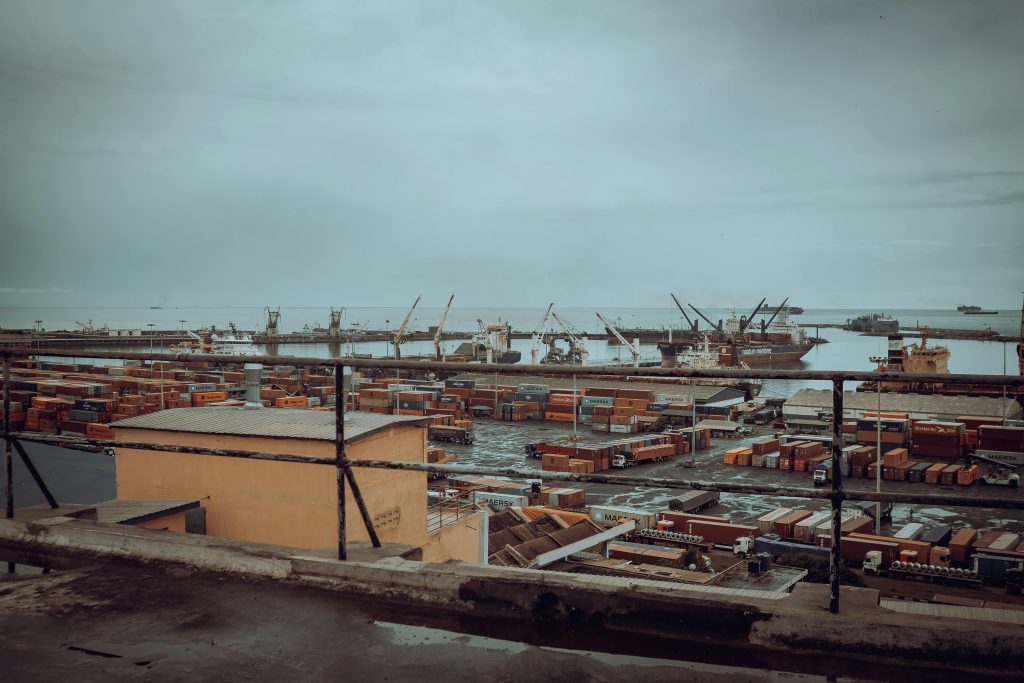 View of Tema Port in Ghana featuring shipping containers and cranes under a cloudy sky.