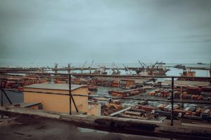 View of Tema Port in Ghana featuring shipping containers and cranes under a cloudy sky.